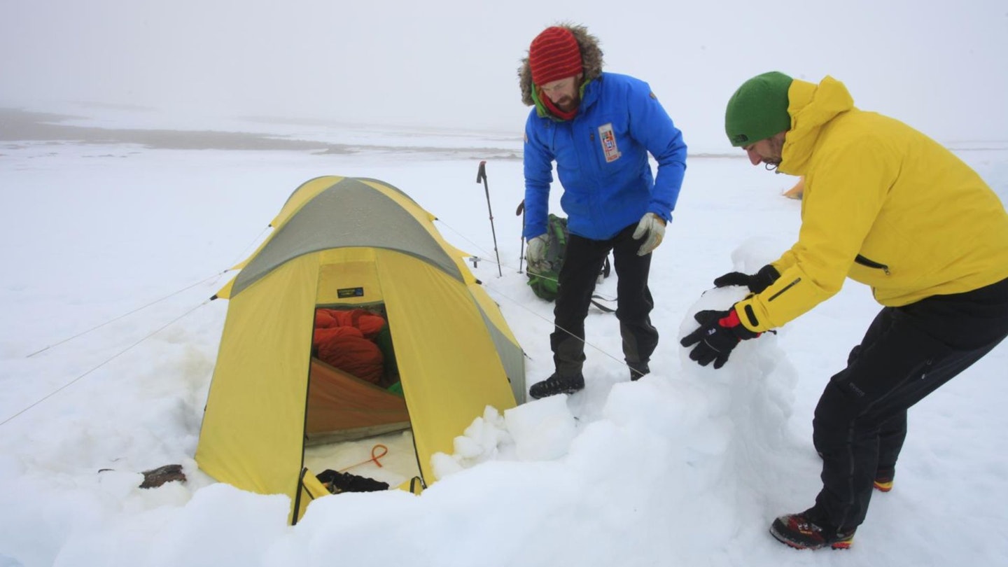 building a snow wall outside the tent