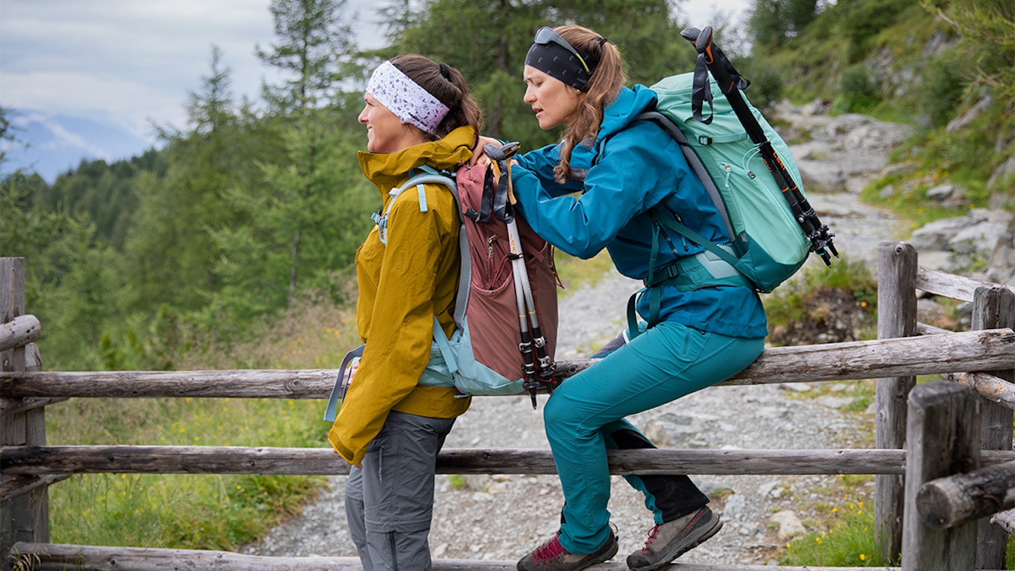 two women adjust a rucksack